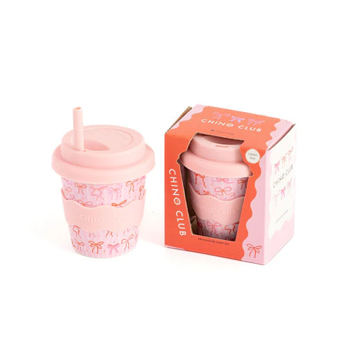 Pink babyccino cup with straw and packaging labeled 'Chino Club' on a white background