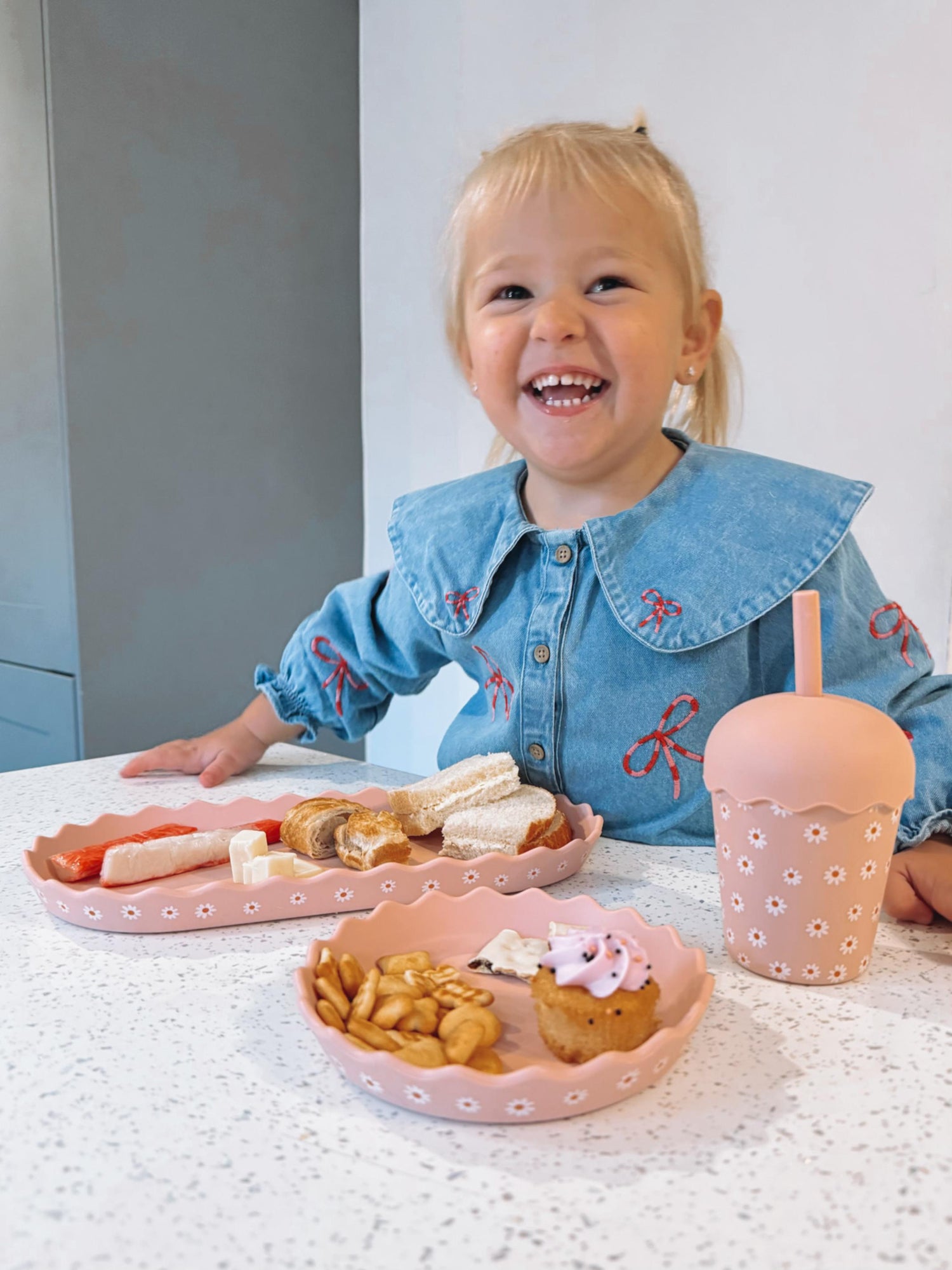 Girl smiling with daisy design chino club plate set and smoothie cup with lid and straw