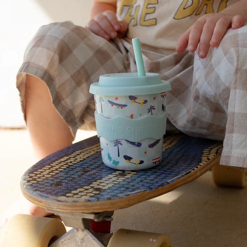 child sitting on skateboard with 8oz midi babyccino cup and light blue aqua straw