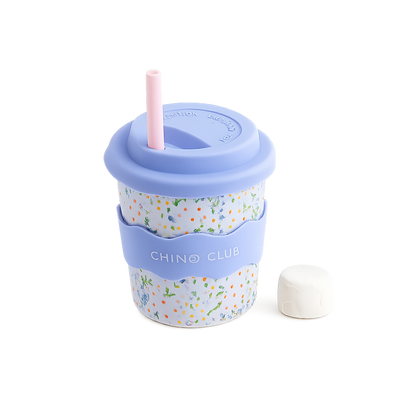 A melamine travel cup with a light blue lid and straw, a floral patterned body, a light blue carrying strap labeled 'CHINO CLUB', and a small white cap placed beside it on a white background.