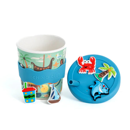 Children's cup with a blue sleeve and colorful lid featuring a crab and dolphin charm on a white background