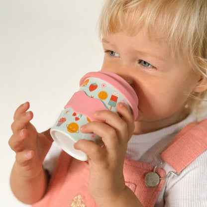 girl holding babyccino cup with pink lid