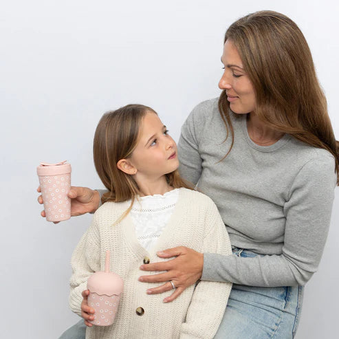 Woman and young girl holding pink chino cups against a light gray background