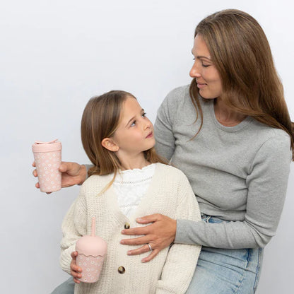 Woman and young girl holding pink chino cups against a light gray background