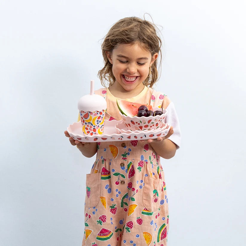 girl holding chino club plate set with reusable smoothie cup in pink fruit design