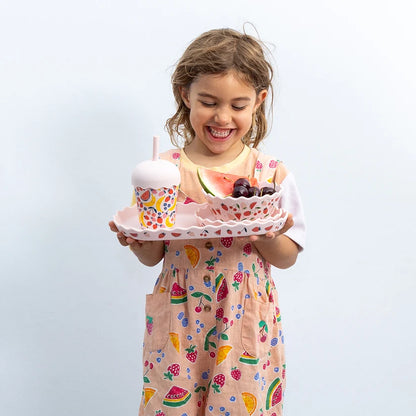 girl holding chino club plate set with reusable smoothie cup in pink fruit design