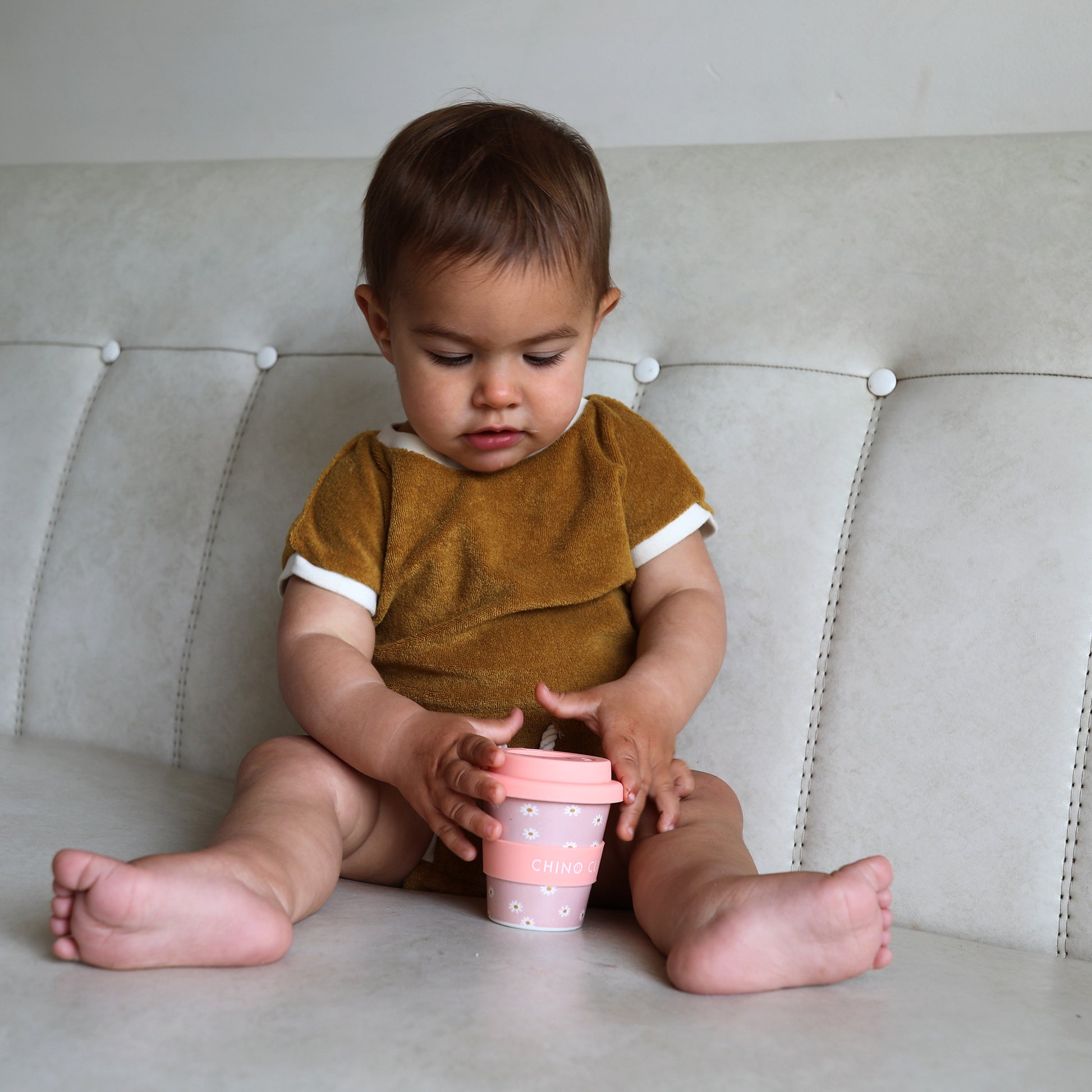 A pink daisy print babychino cup with a toddler