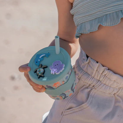 girl holding children’s babychino cup with sea creature charms clipped onto the lid