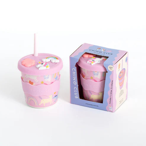 Pink charm cup with straw with unicorn design and straw, accompanied by its packaging on a white background